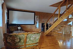 A room with a wooden staircase, a large screen, and a floral-patterned chair.