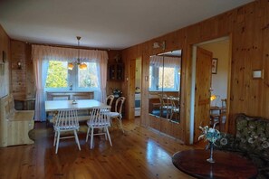 A wooden interior with a dining table, chairs, a sofa, and a small table with a vase. - Half of a Holiday Home, Huge Garden, Pond (gmina Stężyca)