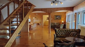 Un interno in legno con una scala, una zona pranzo e un angolo salotto con tavolo e sedie.