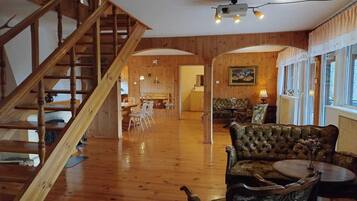 A wooden interior with a staircase, a dining area, and a seating area with a table and chairs.