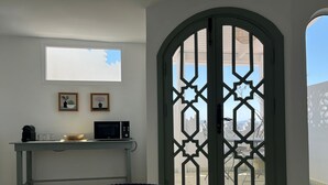 Une pièce comprenant une table avec un plateau en verre, un four à micro-ondes, une machine à café et deux tableaux encadrés accrochés au mur.