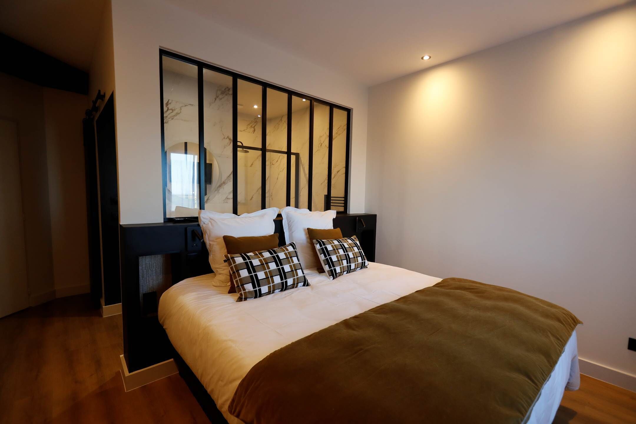 A modern bedroom with a large bed, a headboard with vertical slats, and a mirror above the bed.