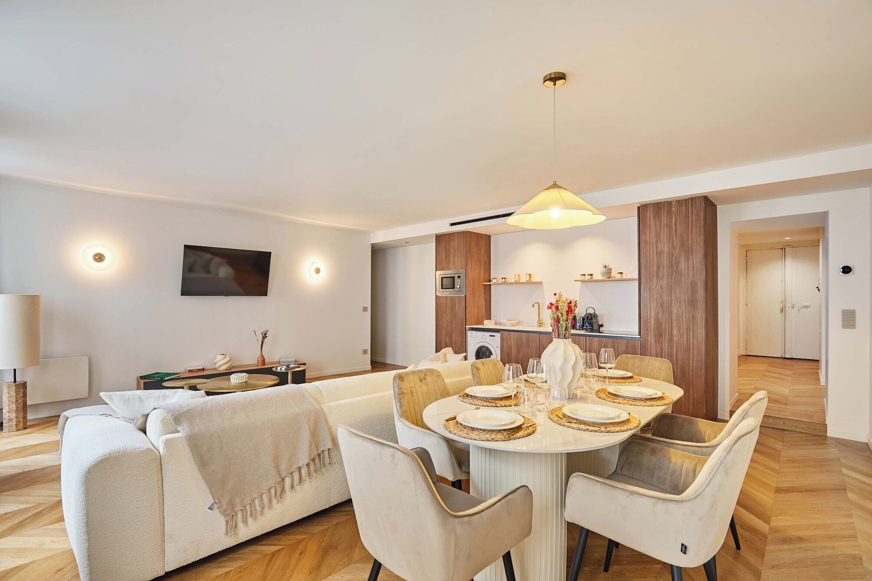 Un salon moderne comprenant un coin repas, un canapé, une table basse et une cuisine en arrière-plan.
