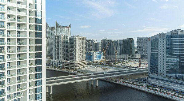 A high-rise building with a modern architectural design, featuring multiple balconies and a river in the foreground.