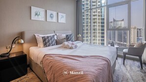 A modern hotel room with a large bed, a nightstand, a chair, and a view of the city through large windows. - Manzil-Waterfront Studio in Business Bay (Dubai)