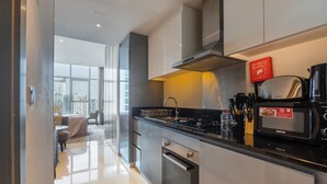 A modern kitchen with stainless steel appliances, a black countertop, and a view of the city through large windows. - Manzil-Waterfront Studio in Business Bay (Dubai)