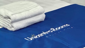 A neatly made bed with white linens and a blue blanket with 'UnicentroRooms' branding. - Beautiful house located in north Bogota (Bogotá, D.C.)