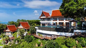 A large resort with multiple buildings, a swimming pool, and lush greenery.