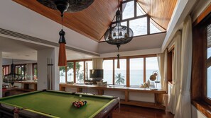 A pool table with balls, a television, and a view of the ocean.