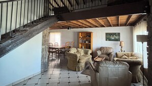 A spacious living area with a high ceiling, a staircase, and a dining area. - Casa Vacacional Marqués (Playas de Rosarito)