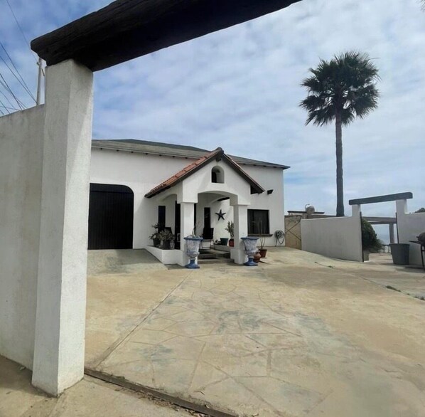 A white house with a tiled roof and a palm tree in the background. - Casa Vacacional Marqués (Playas de Rosarito)