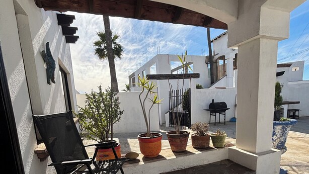 A covered patio area with a black folding chair, potted plants, and a grill. - Casa Vacacional Marqués (Playas de Rosarito)