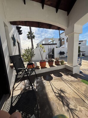 A covered patio area with a black folding chair, potted plants, and a grill. - Casa Vacacional Marqués (Playas de Rosarito)