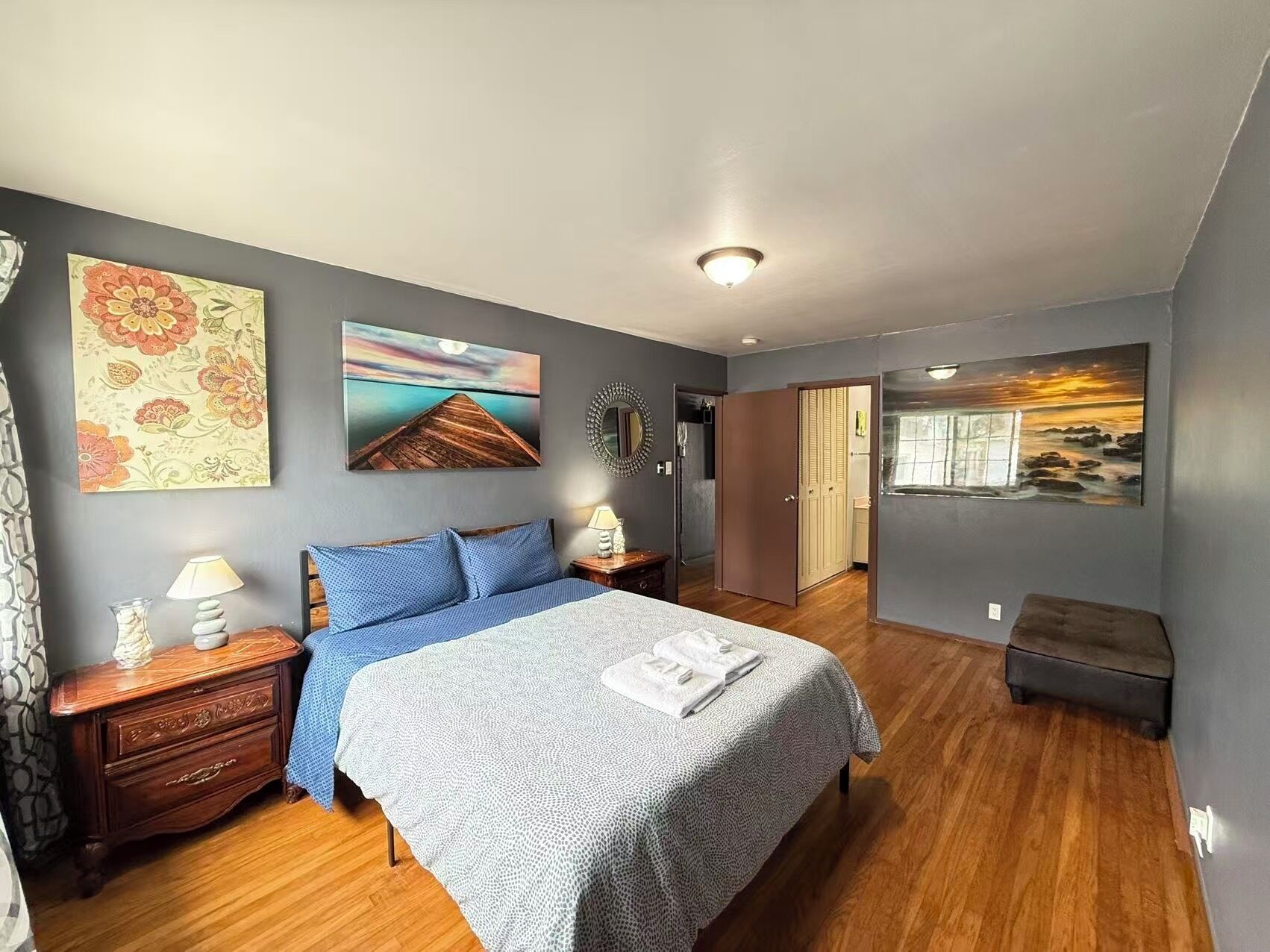 Une chambre à coucher comprenant un lit, des tables de chevet, une commode et des œuvres d’art accrochées aux murs.