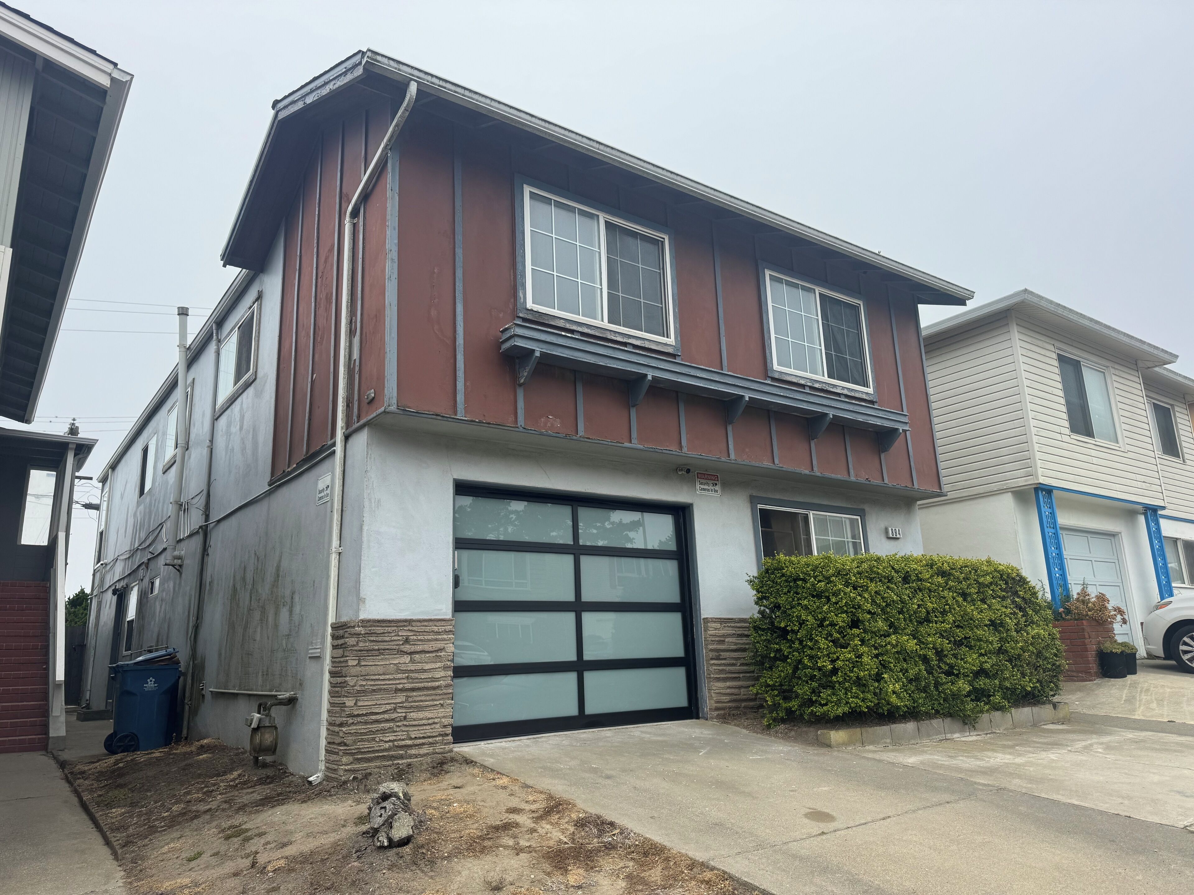 A two-story house with a garage, a stone foundation, and a well-maintained lawn.