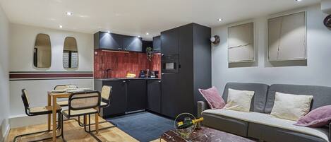Un espacio habitable compacto con comedor, kitchenette y un sofá con cojines.