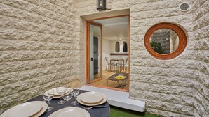 A dining area with a table set for four, a glass door leading to a dining room, and a round mirror on the wall. - Charming Apartment Faubourg St Honore Madeleine (Paris)