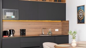 A modern kitchen with a microwave, coffee maker, and sink. There is a dining table with placemats and a vase with plants. - Seaview Apartment w/ Jacuzzi – Makarska (Makarska)