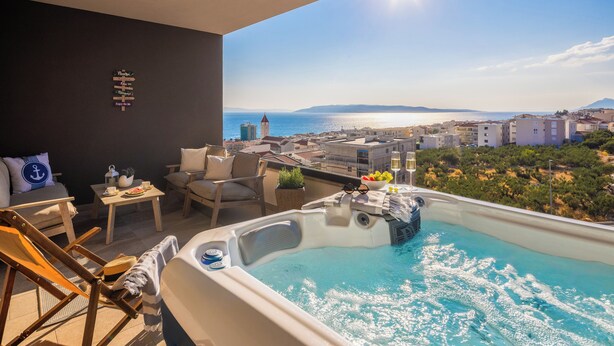 A rooftop terrace with a hot tub, seating area, and a view of the sea and cityscape. - Seaview Apartment w/ Jacuzzi – Makarska (Makarska)