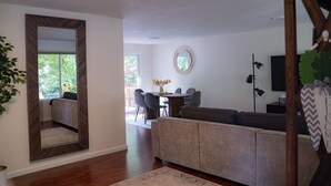 A living room with a large mirror, a dining area with a table and chairs, a sofa, and a television. - Forest Escape – Hiking & Rattlesnake Lake Nearby (North Bend)