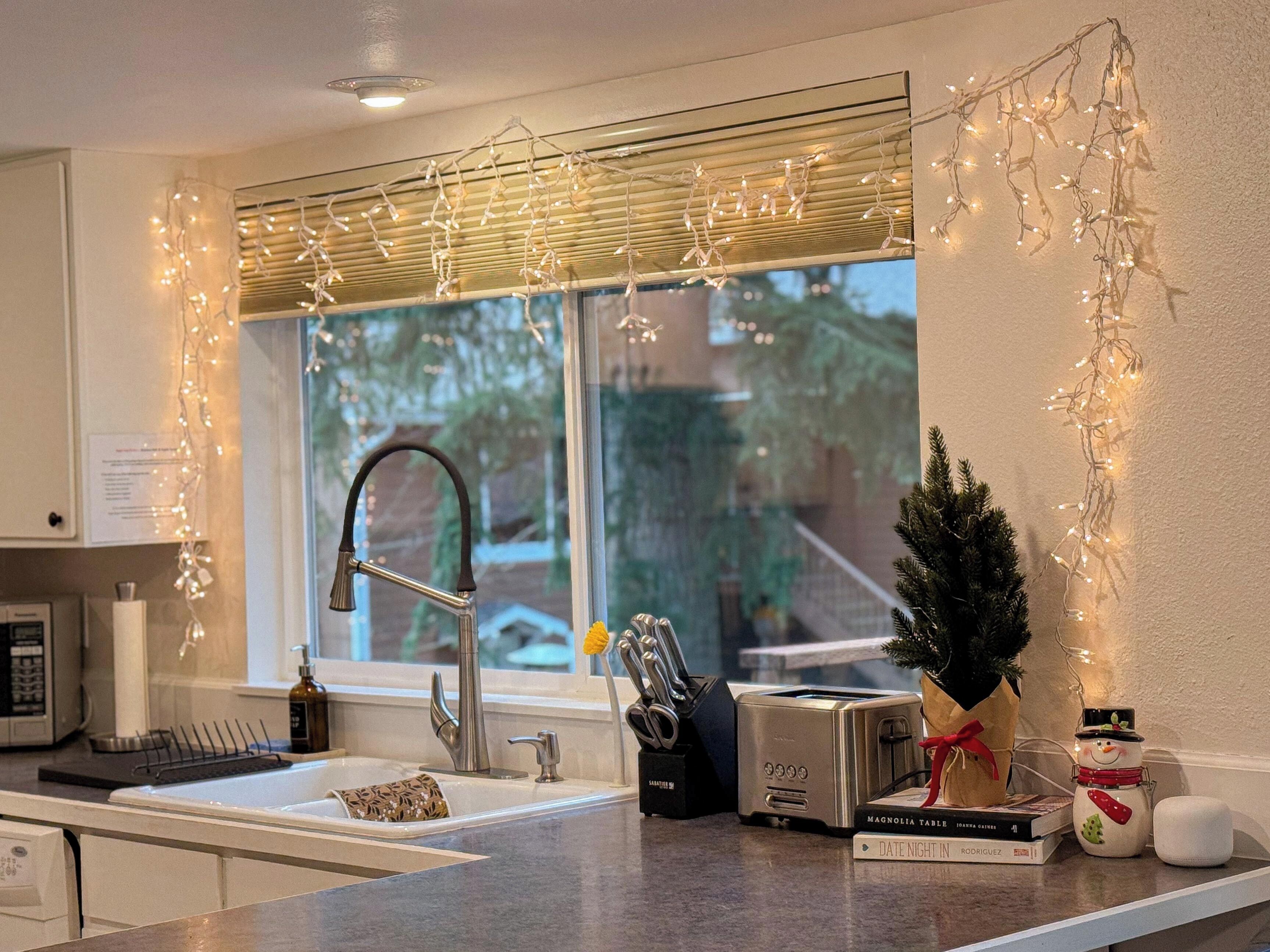 A kitchen with a modern faucet, a toaster, and a small Christmas tree.