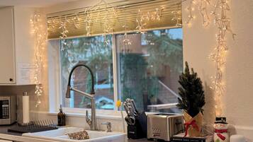 A kitchen with a modern faucet, a toaster, and a small Christmas tree.
