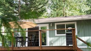 A covered deck with outdoor furniture, a grill, and a window overlooking a wooded area. - Forest Escape – Hiking & Rattlesnake Lake Nearby (North Bend)