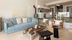 A modern living room with a light blue sofa, a wooden coffee table, and a black ottoman.