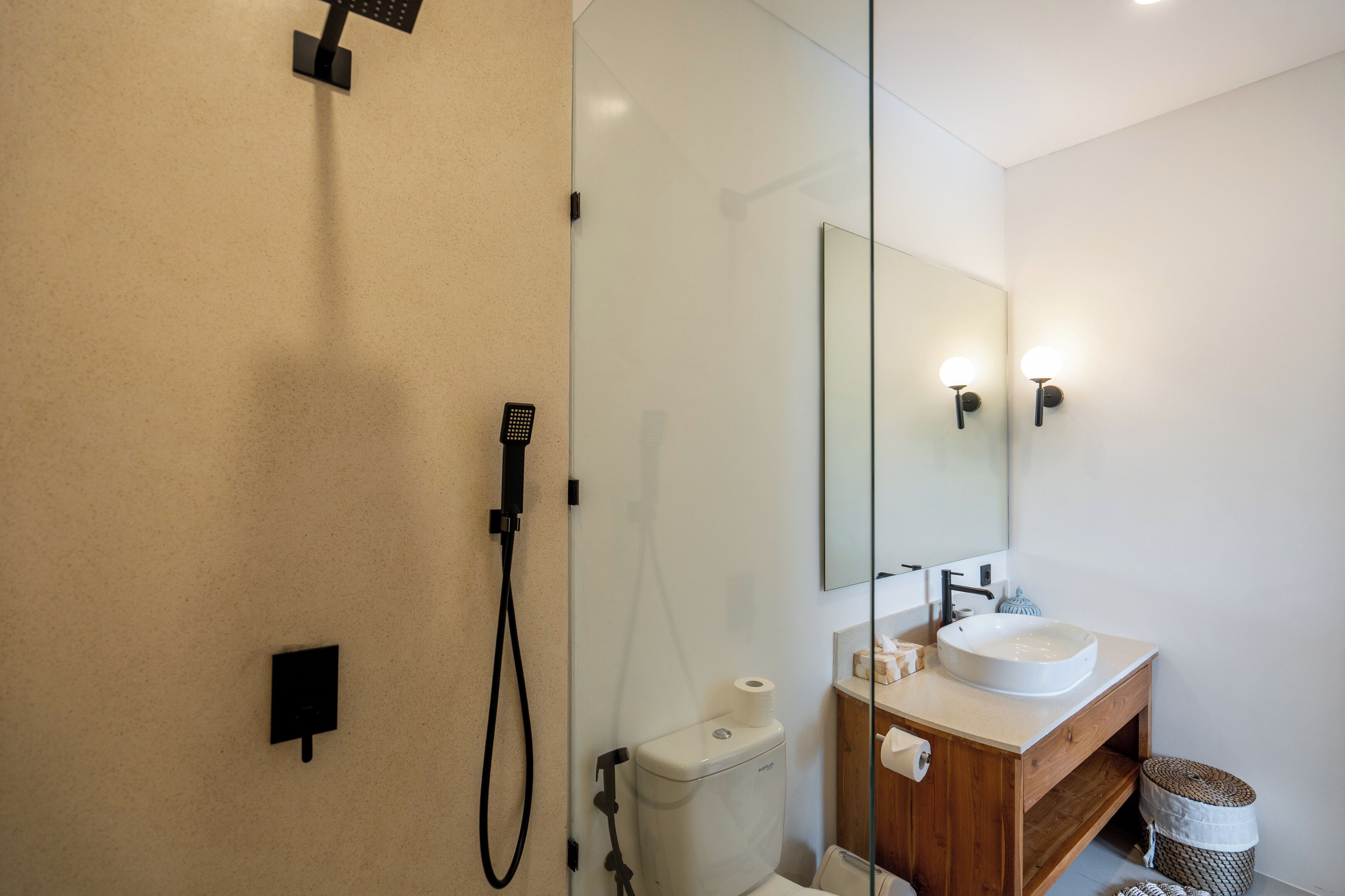 A modern bathroom with a glass shower enclosure, a white sink, and a wooden vanity.