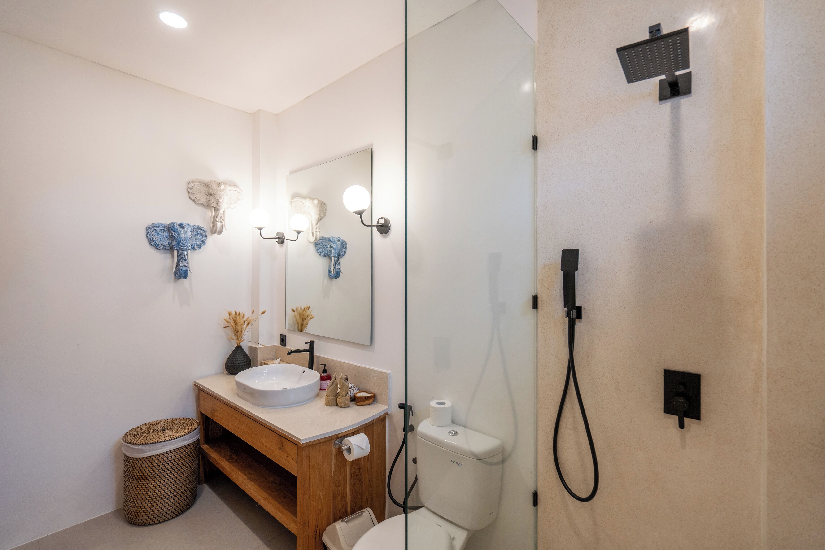 Un baño moderno con tocador de madera, un espejo grande y cabina de ducha con mampara de vidrio.