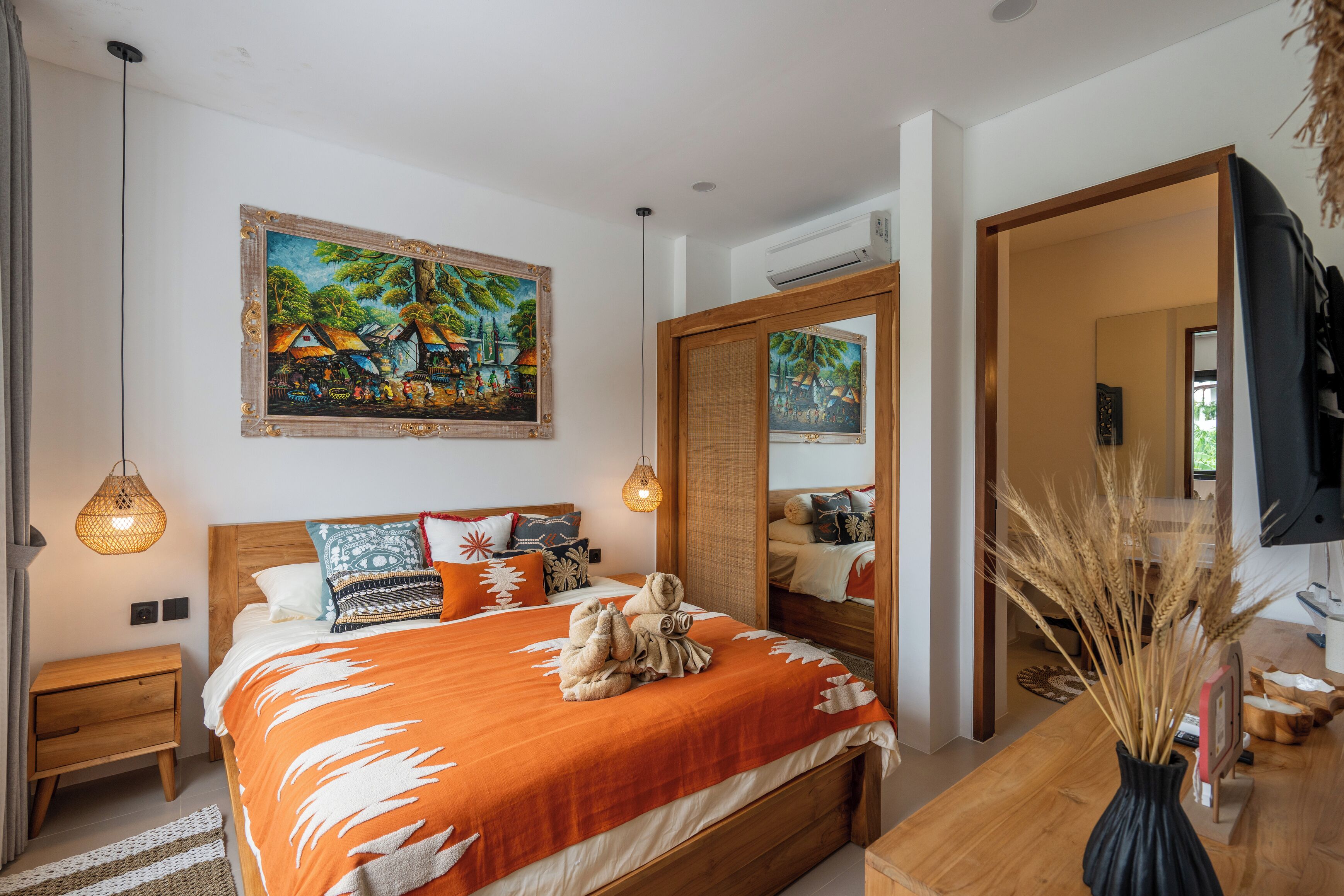 Un dormitorio moderno con una cama grande, cabecera de madera, un cuadro sobre la cama y un espejo en la pared.