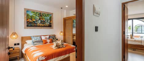 A bedroom with a wooden bed, a painting on the wall, and a view through an open door.