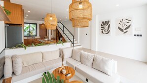 A modern living room with a sofa, a coffee table, and hanging rattan lights. - Amal Villas by Bali Bliss Properties (Canggu)