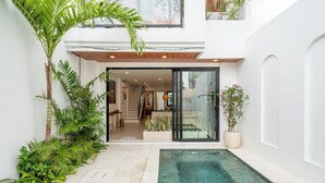A modern house with a glass door entrance, a small pool, and lush greenery. - Amal Villas by Bali Bliss Properties (Canggu)