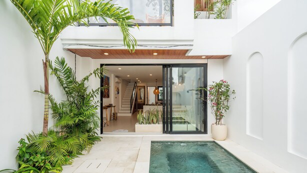 A modern house with a glass door entrance, a small pool, and lush greenery. - Amal Villas by Bali Bliss Properties (Canggu)