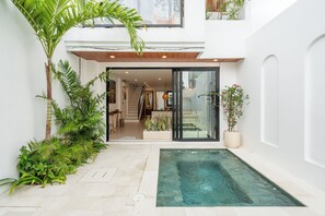A modern house with a glass door entrance, a small pool, and lush greenery. - Amal Villas by Bali Bliss Properties (Canggu)