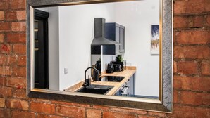 Eine Küche mit modernem Design, ausgestattet mit einem schwarzen Spülbecken, Edelstahlgeräten und einer Holz Arbeitsplatte.