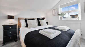 A bedroom with a bed, a nightstand, a window with a view, and a potted plant.