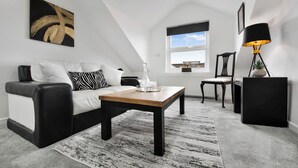A modern living room with a black and white sofa, a wooden coffee table, and a black floor lamp.
