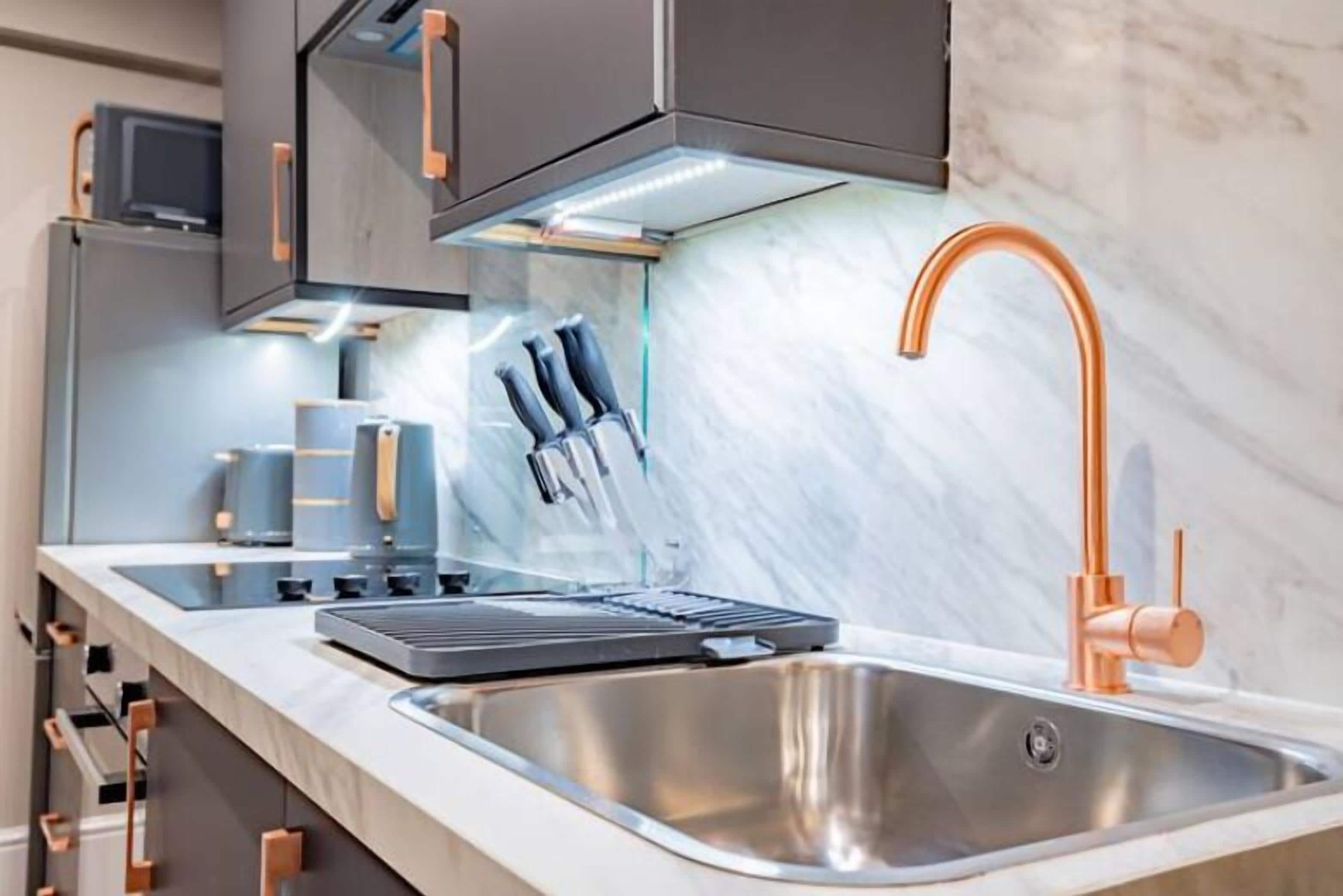 A modern kitchen with a stainless steel sink, copper faucet, and a built-in oven.