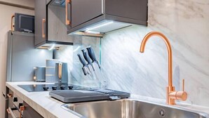 A modern kitchen with a stainless steel sink, copper faucet, and a built-in oven. - WhiskAwayHomes Shaw Street Apartment 2 (Worcestershire)