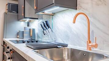 A modern kitchen with a stainless steel sink, copper faucet, and a built-in oven.