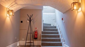 A staircase with a fire extinguisher and a ladder in a hallway with a white ceiling and wall sconces. - WhiskAwayHomes Shaw Street Apartment 2 (Worcestershire)