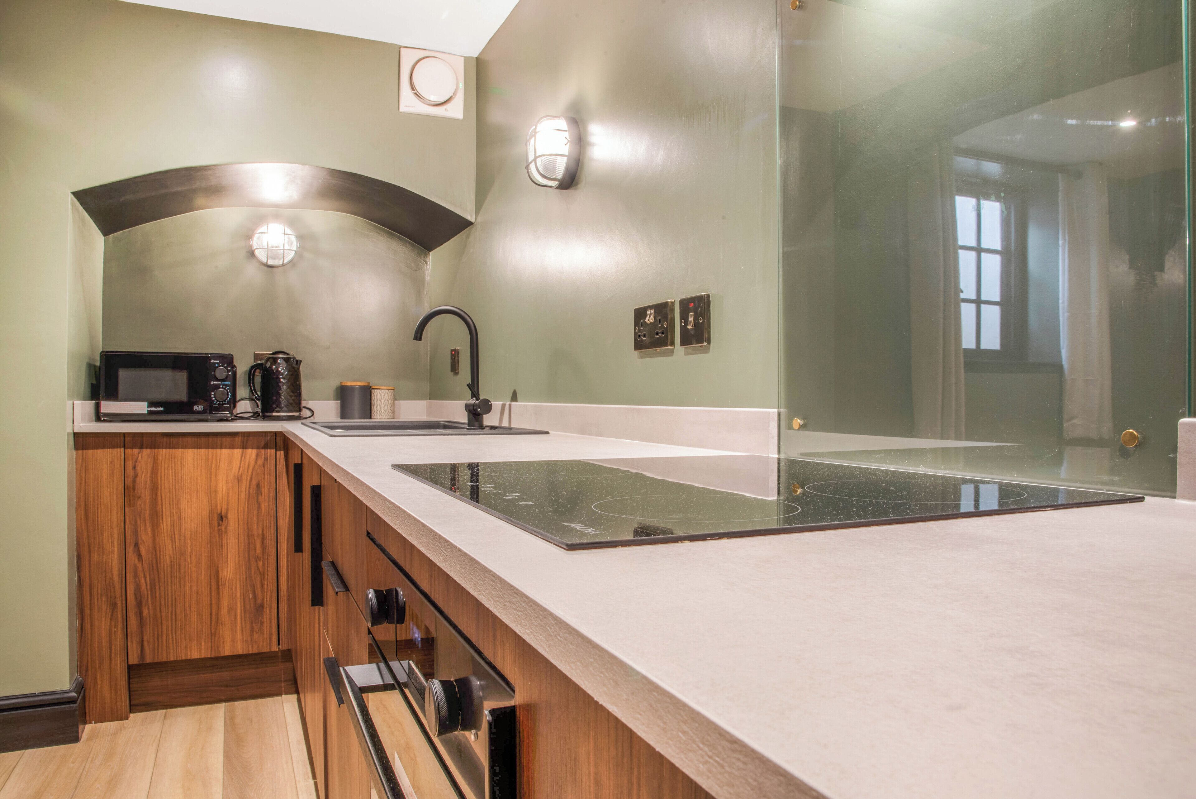 A modern kitchen with a large island, wooden cabinets, and a microwave.