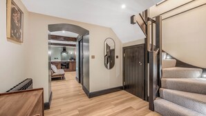 Un interior moderno con suelo de madera, una escalera y una zona de cocina visible a través de un arco.