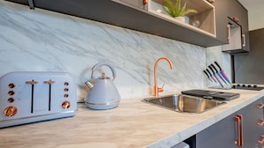 Eine moderne Küche mit Marmorarbeitsplatte, einem Wasserkocher, einem Toaster und einem Spülbecken.