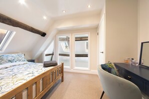 A bedroom with a bed, a desk, and a chair. There is a window and a door. - WhiskAwayHomes Vinegar House No. 7 (Worcestershire)