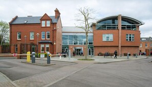 A modern building with a brick facade and large windows, featuring a curved glass section. - WhiskAwayHomes Vinegar House No. 7 (Worcestershire)