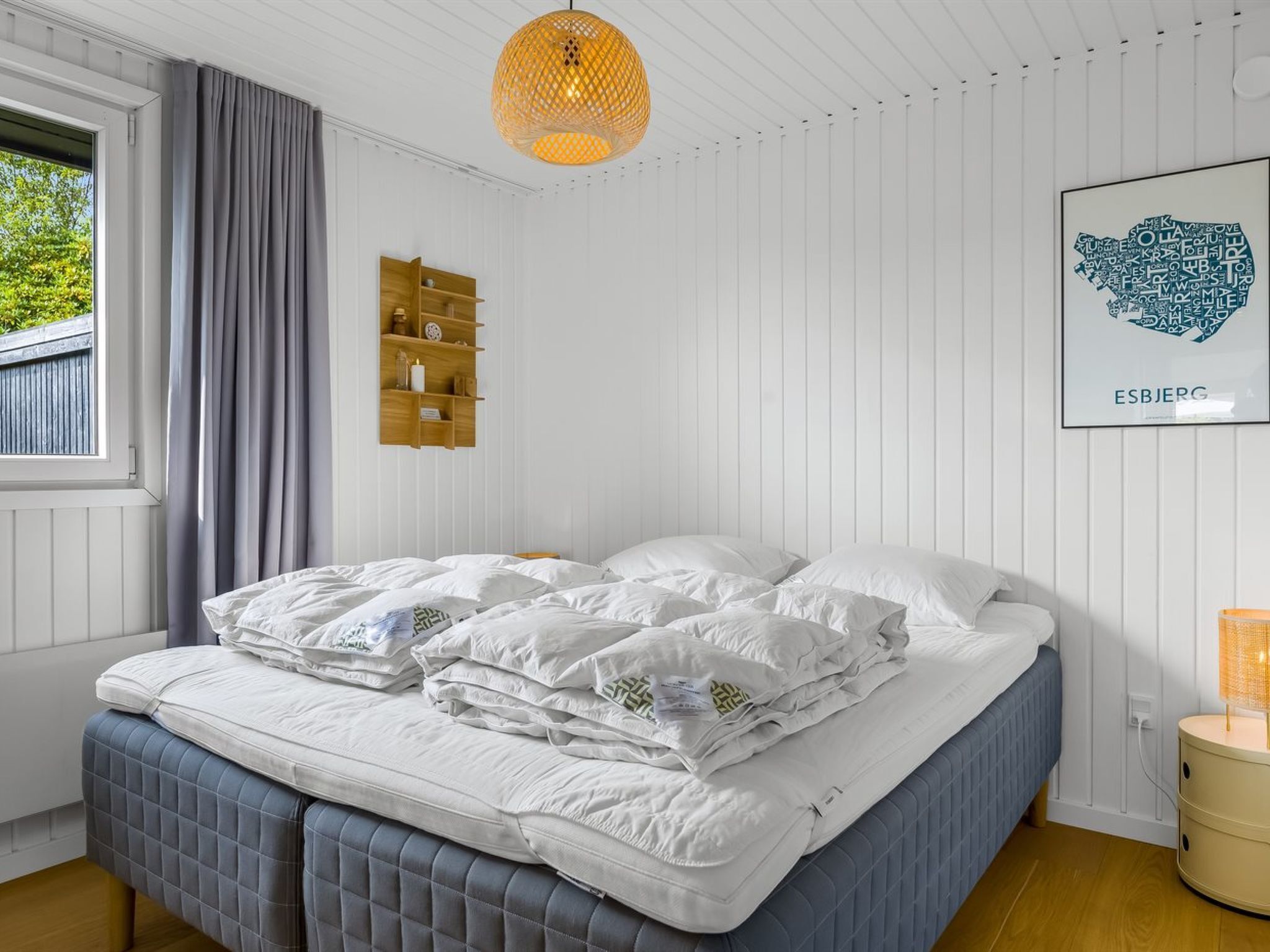 Una camera da letto con un letto, una lampada a sospensione, uno scaffale a muro e un quadro incorniciato.