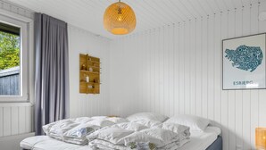 Un dormitorio con cama, lámpara colgante, estante en la pared y un cuadro enmarcado.